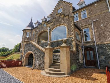 The exterior of a stone building with arched windows and a staircase leading to an upper level at On the Straits in Glyngarth near Menai Bridge