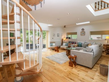 A living room with a spiral staircase wooden floor gray sofa and glass coffee table at On the Straits in Glyngarth near Menai Bridge