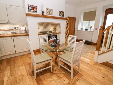 A kitchen and dining area with a glass top table and four chairs at On the Straits in Glyngarth near Menai Bridge