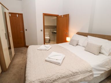 A bedroom with a bed and two towels folded on a quilt at On the Straits in Glyngarth near Menai Bridge