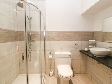 A bathroom with a glass shower enclosure a white toilet and a countertop sink at On the Straits in Glyngarth near Menai Bridge