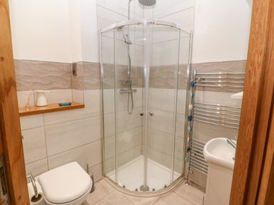 A bathroom with a corner shower enclosure a toilet a towel rack and a sink at On the Straits in Glyngarth near Menai Bridge