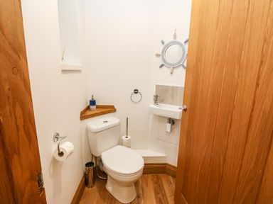 A small bathroom with a toilet sink and wooden door at On the Straits in Glyngarth near Menai Bridge