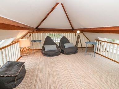 An attic seating area with two bean bag chairs two small tables and two lamps at On the Straits in Glyngarth near Menai Bridge