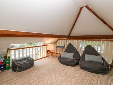 A loft area with two grey bean bags and a rectangular bean bag next to a lamp and small table at On the Straits in Glyngarth near Menai Bridge