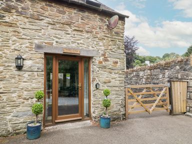 Entrance door in a stone building with two potted plants and a wooden gate at Miller's Lodge in St Keyne near Liskeard