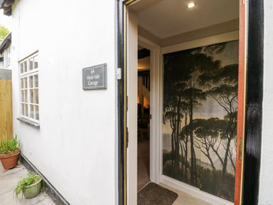 An open door showing the entrance with a wall mural of trees inside at Hock-tide Cottage in Kenilworth