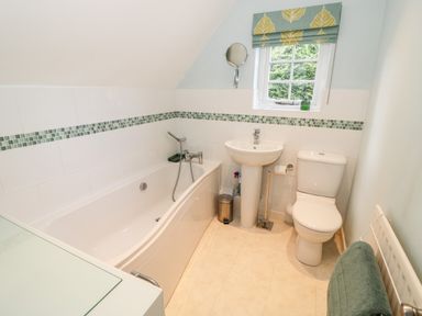 A bathroom with a bathtub sink toilet and a window with blinds at Hock-tide Cottage in Kenilworth