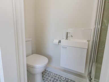 A bathroom with a toilet a sink and a shower at Castle Cove Cottage in Weymouth