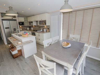 A kitchen and dining area with a dining table and chairs a kitchen island and appliances at No 27 The Crab Pot in Runswick Bay near Staithes