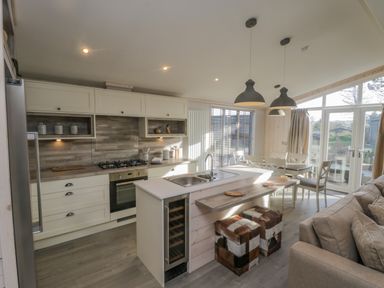A kitchen and dining area with stove and sink and stools at No 27 The Crab Pot in Runswick Bay near Staithes