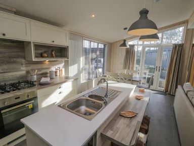 A kitchen with a sink island and dining table near large windows and a couch at No 27 The Crab Pot in Runswick Bay near Staithes