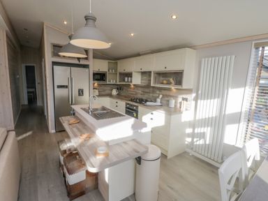 A kitchen with white cabinets a wooden countertop a double refrigerator and two pendant lights at No 27 The Crab Pot Runswick Bay near Staithes