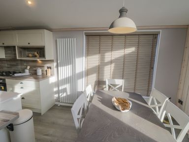 A kitchen dining area with a table and chairs next to a window with blinds at No 27 The Crab Pot Runswick Bay near Staithes