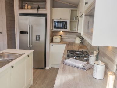 A kitchen with a double door refrigerator a microwave oven a gas stove sink and wooden countertops at No 27 The Crab Pot Runswick Bay near Staithes