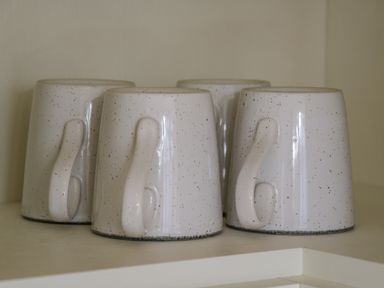 Four upside down ceramic mugs with speckled design on a shelf at No 27 The Crab Pot in Runswick Bay near Staithes