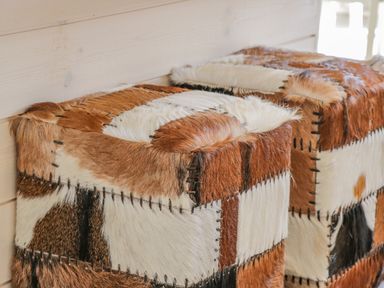 Two square ottomans covered in patchwork animal fur against a wooden wall at No 27 The Crab Pot in Runswick Bay near Staithes