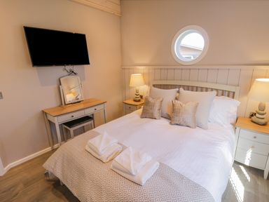 A bedroom with a bed with pillows and towels bedside tables with lamps a television and a dressing table at No 27 The Crab Pot in Runswick Bay near Staithes