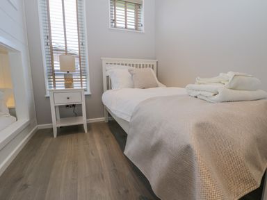 A bedroom with a single bed bedside table lamp and folded towels at No 27 The Crab Pot Runswick Bay near Staithes
