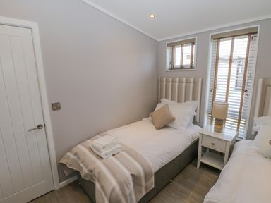A bedroom with two single beds a bedside table and windows with blinds at No 27 The Crab Pot in Runswick Bay near Staithes