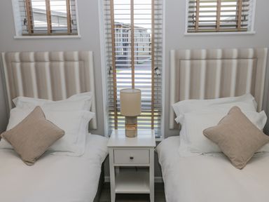 A bedroom with two single beds and a nightstand with a lamp between them at No 27 The Crab Pot in Runswick Bay near Staithes