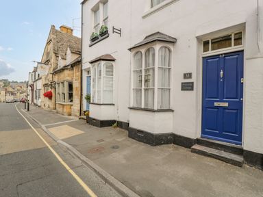 A street view with white cottages and a blue door marked 33 at Primrose Cottage in Winchcombe