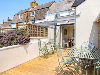 An outdoor patio area with green metal tables and chairs next to a white building at Blanche Cottage Brewers Quay Harbour