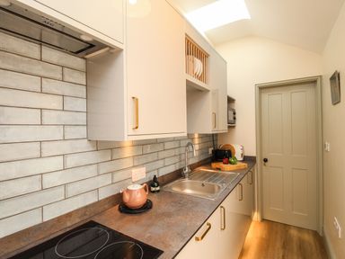 A narrow kitchen with countertop appliances and a sink at Blanche Cottage in Brewers Quay Harbour