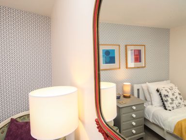 A bedroom with a bed a nightstand with a lamp and framed artwork on the wall at Blanche Cottage Brewers Quay Harbour
