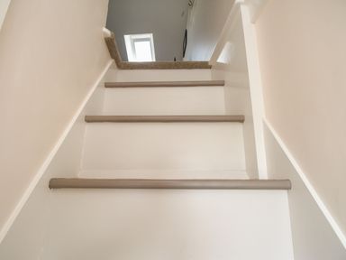 A close up of white stairs with grey edges and beige walls at Blanche Cottage Brewers Quay Harbour