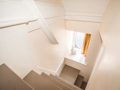 A stairway with gray steps and a white ceramic rabbit on the window sill at Blanche Cottage Brewers Quay Harbour