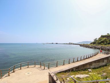 A waterfront walkway with railings overlooking the sea and a rocky shoreline at Blanche Cottage in Brewers Quay Harbour