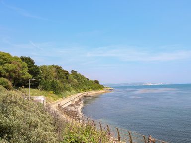 A coastal path with railing beside the sea and greenery on the left at Blanche Cottage in Brewers Quay Harbour