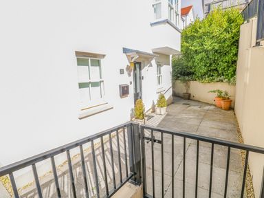 A gated entrance leading to a front door with potted plants and a window at Puffins in Tenby