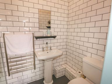 A bathroom with a pedestal sink mirror towel rack toilet and tiled walls at Nightingale Cottage in Lostwithiel