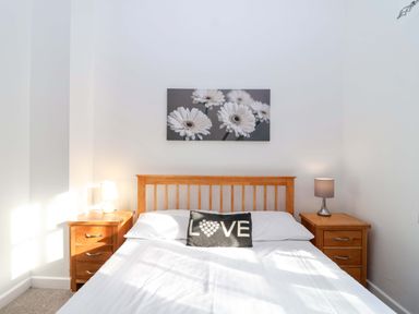 A bedroom with a bed and nightstands at Nest Cottage in St Tudy