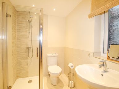 A bathroom with a shower enclosure a toilet a sink and a window at Pams House in Weymouth