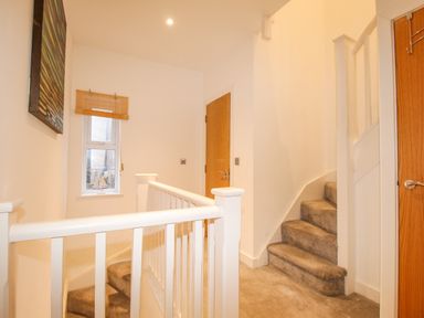 A carpeted staircase with white banisters and wooden doors at Pam's House in Weymouth