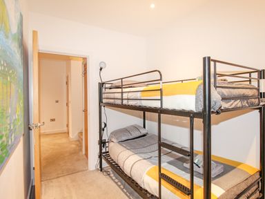 A bedroom with a metal bunk bed and an open door showing a hallway at Pams House in Weymouth