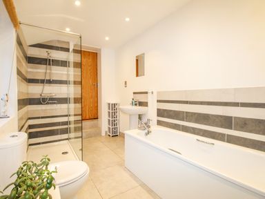 A bathroom with a bathtub sink toilet shower area and storage unit at Pams House in Weymouth