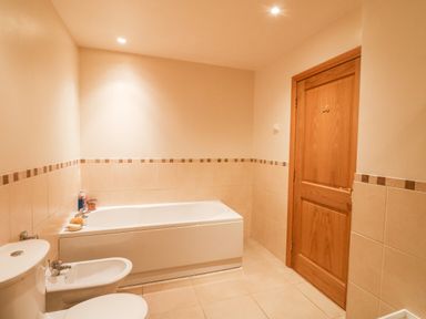 A bathroom with a bathtub toilet bidet and wooden door at Ptarmigan Lodge in Glengoulandie near Aberfeldy