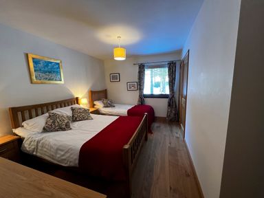 A bedroom with two beds wooden furniture curtains and a window at Ptarmigan Lodge in Glengoulandie near Aberfeldy