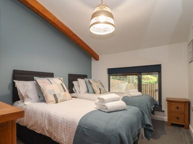 A bedroom with two single beds with folded towels on them and a window with a blind at Tolcarne in Porthtowan