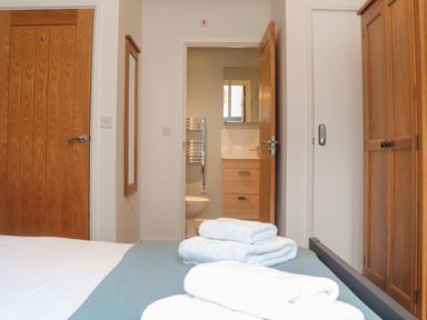 A bedroom with a bed with towels on it a wooden door a mirror on the wall and a wardrobe at Tolcarne in Porthtowan
