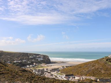 A coastal village with houses between hills and a beach at Tolcarne in Porthtowan