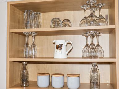 Wooden shelves with various glassware a pitcher with a cow design and containers labeled tea sugar and coffee at Celyn in Cyffylliog