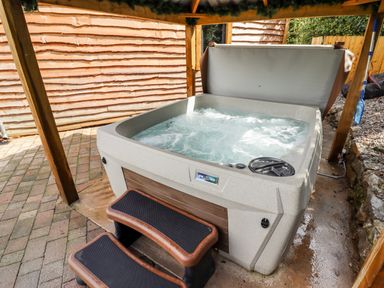 An outdoor hot tub with steps under a wooden canopy at Celyn in Cyffylliog