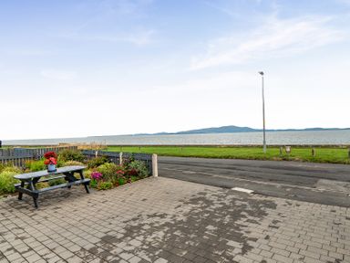 An outdoor area with a table and flowers overlooking the sea at Solway View in Skinburness near Silloth