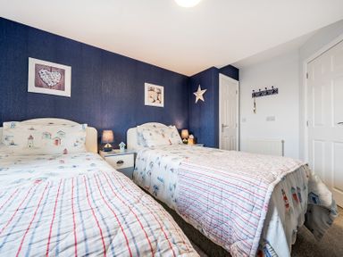 A bedroom with two beds and pictures on the wall at Solway View in Skinburness near Silloth