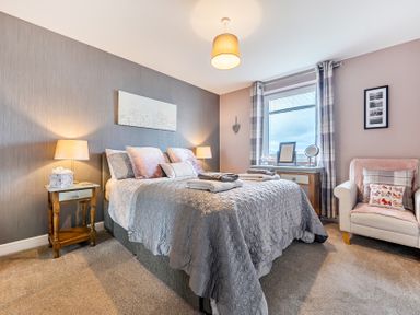 A bedroom with a bed, nightstand, and a window at Solway View in Skinburness near Silloth